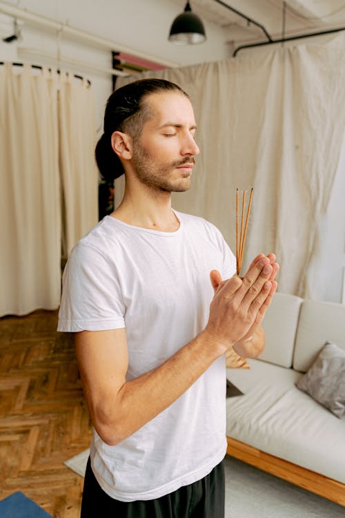 A Man in White Shirt Holding an Incense Sticks with His Eyes Closed