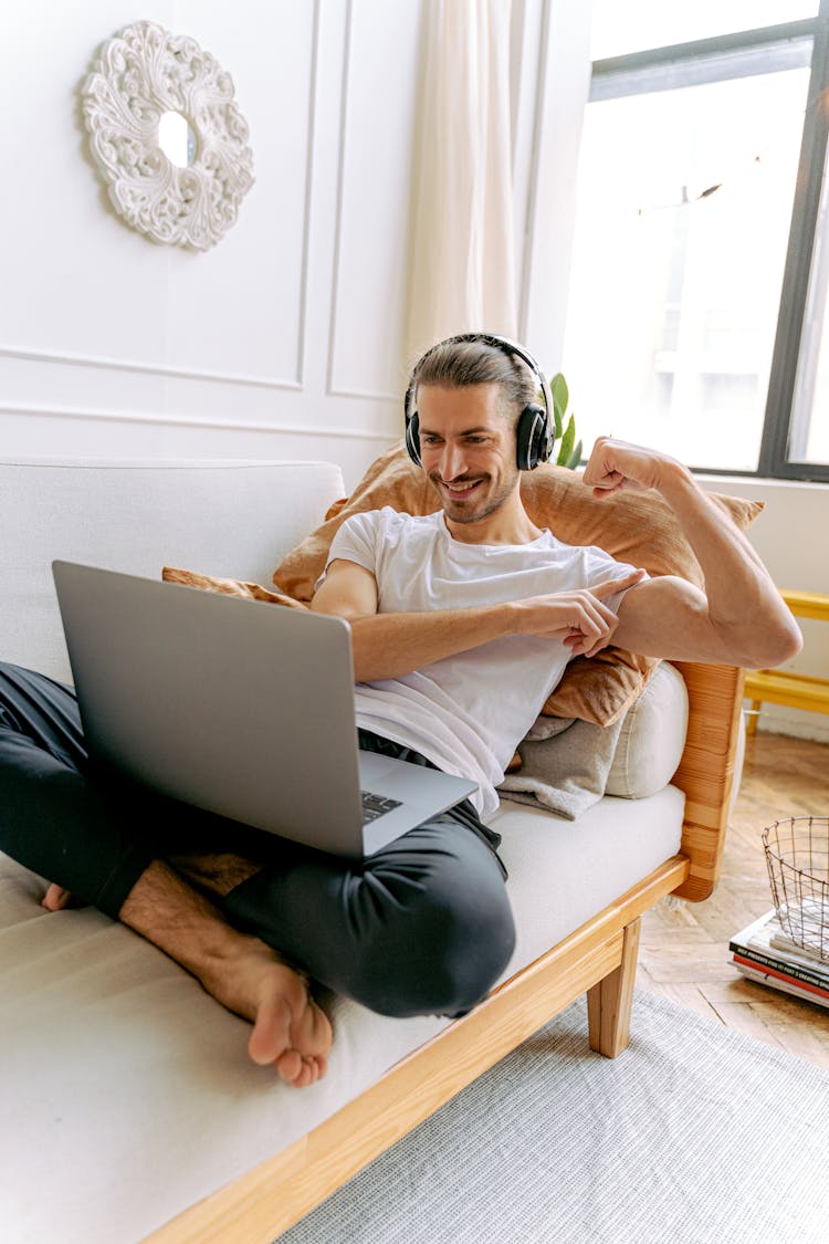 A Man Sitting On The Couch While Flexing His Muscles