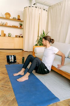 Adult man exercising at home using online video guidance on a laptop.