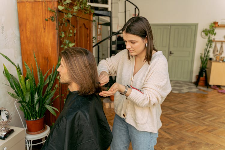 A Woman Combing The Hair Of A Bearded Man