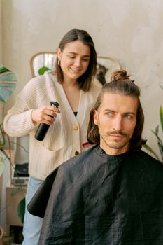 Woman stylist giving a stylish haircut to a male client in a modern salon setting.