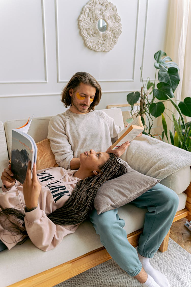 Couple Lounging On Sofa Reading Books