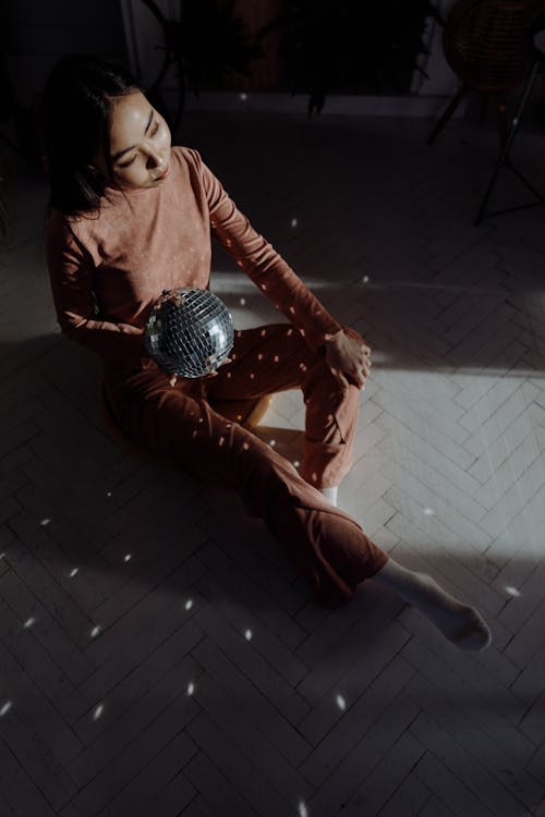 A Woman Sitting while Holding a Disco Ball