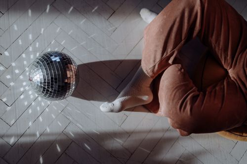 Free A person sitting on the floor with a disco ball casting reflections from above. Stock Photo