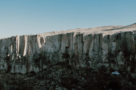 Stunning rocky cliff landscape with clear blue sky, perfect for adventure and nature photography.