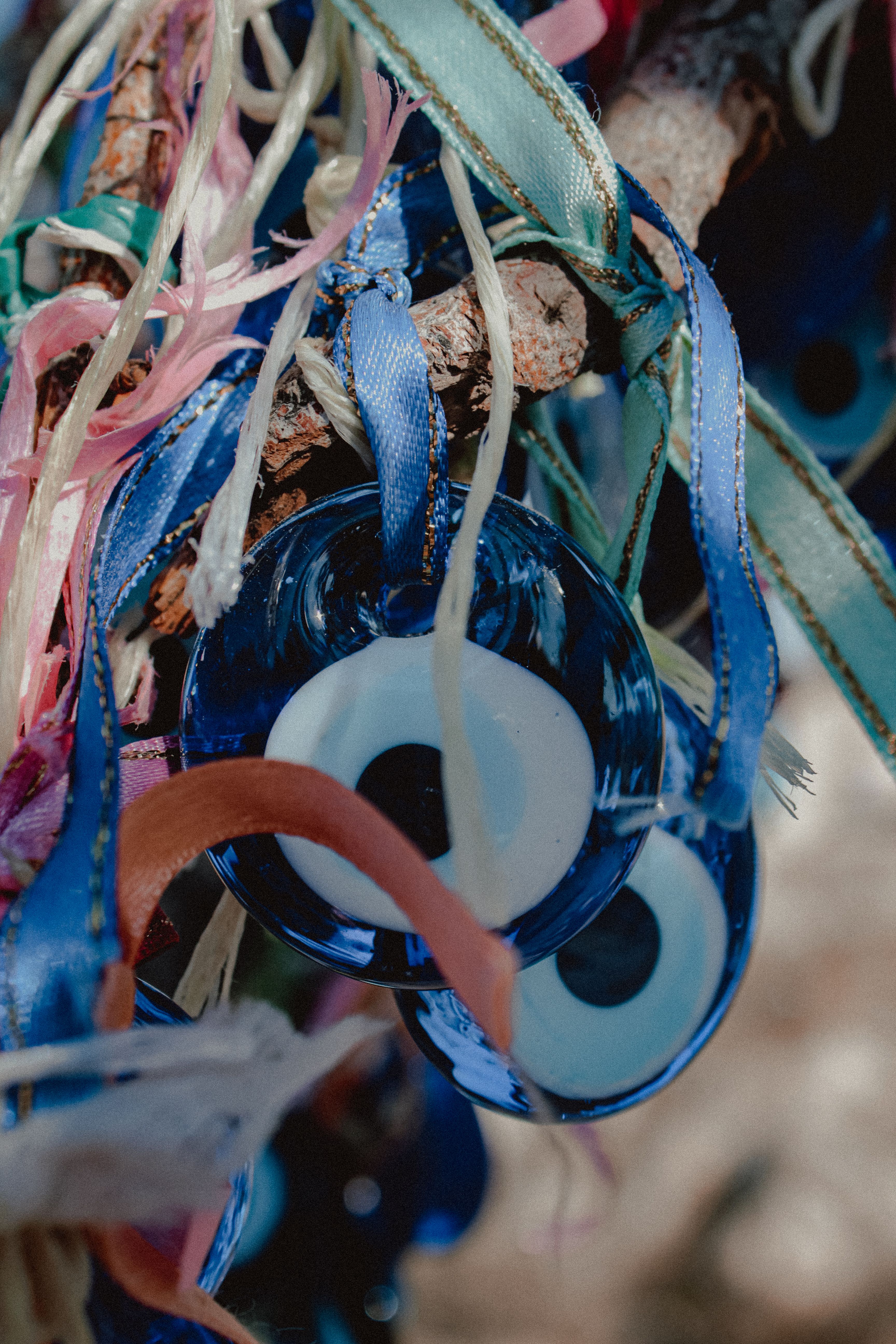 Close-up of vibrant evil eye talismans and ribbons on a branch in Nevşehir, Turkey.