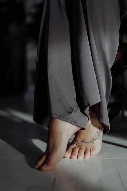 Free Graceful close-up of tattooed feet tiptoeing in soft natural light, conveying elegance and mystery. Stock Photo