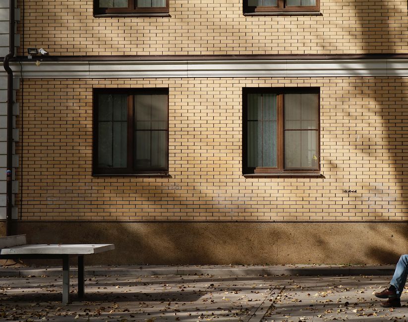 Serene view of a brick building exterior with autumn shadows and a solitary bench.