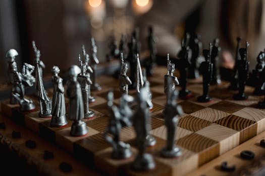 Detailed close-up of metallic chess pieces on a wooden board, showcasing a strategic game in progress.