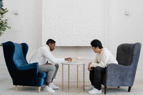 Free Two Men Playing Chess While Sitting in Armchairs Beside White Wall Stock Photo