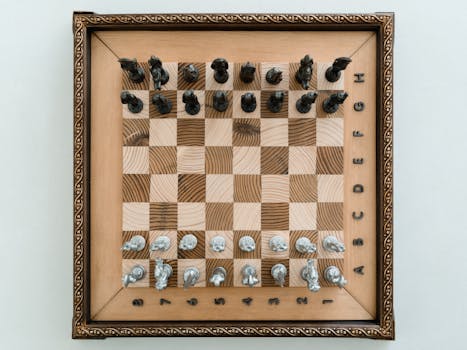 Top view of a vintage wooden chess board with metal pieces arranged for game play.