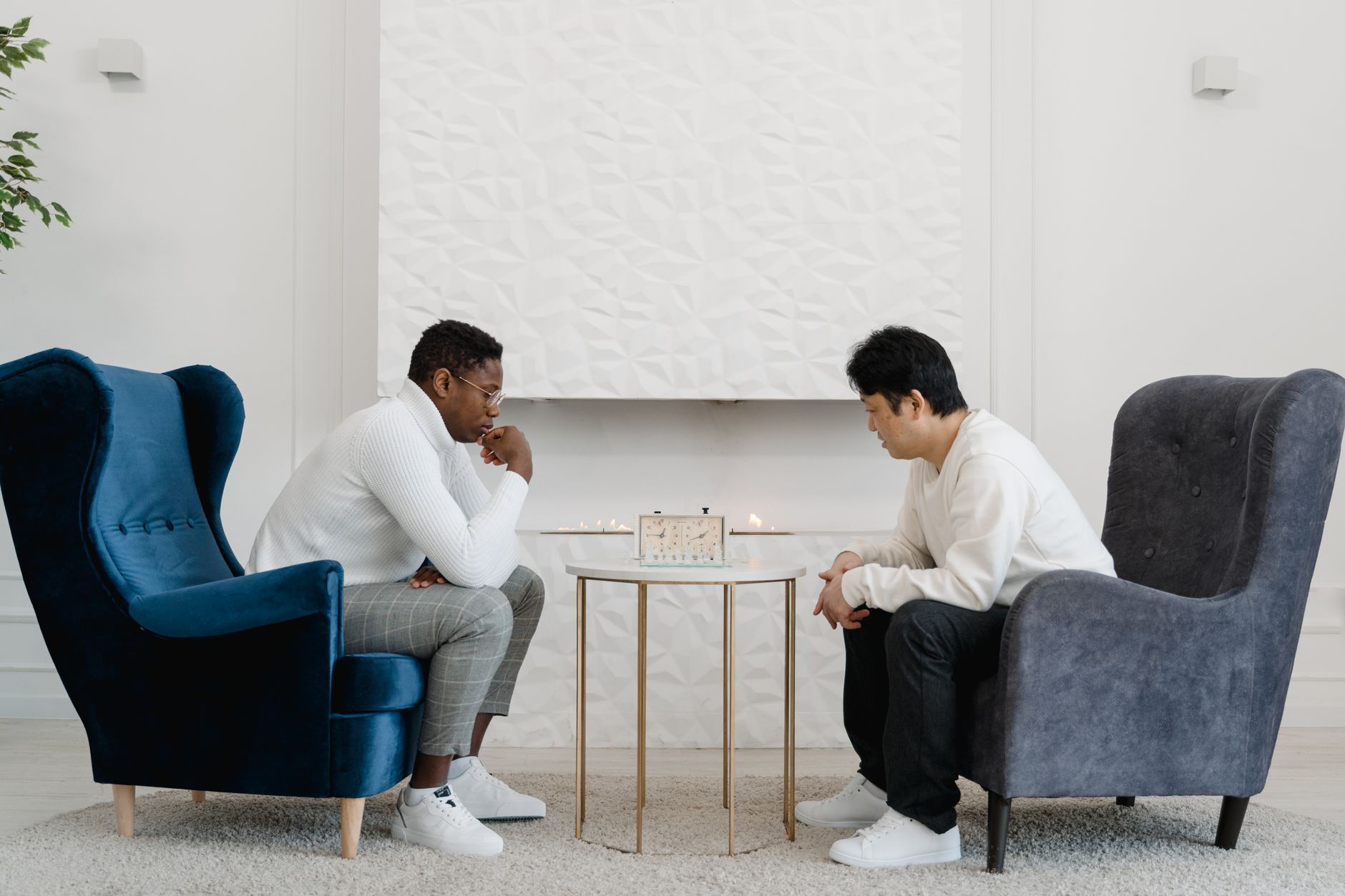 Two men engaged in a focused chess match indoors with a minimalistic aesthetic.