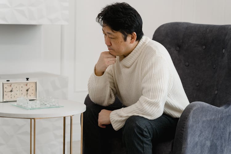 Man Sitting In White Sweater Playing Chess Game