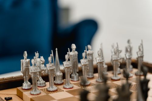 Free Silver soldier-themed chess pieces arranged on a wooden board in a cozy setting. Stock Photo