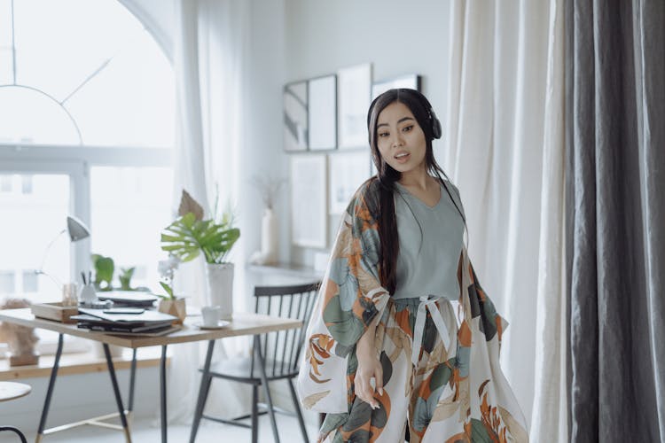 A Woman  With Headphones Singing And Dancing In The Dining Room