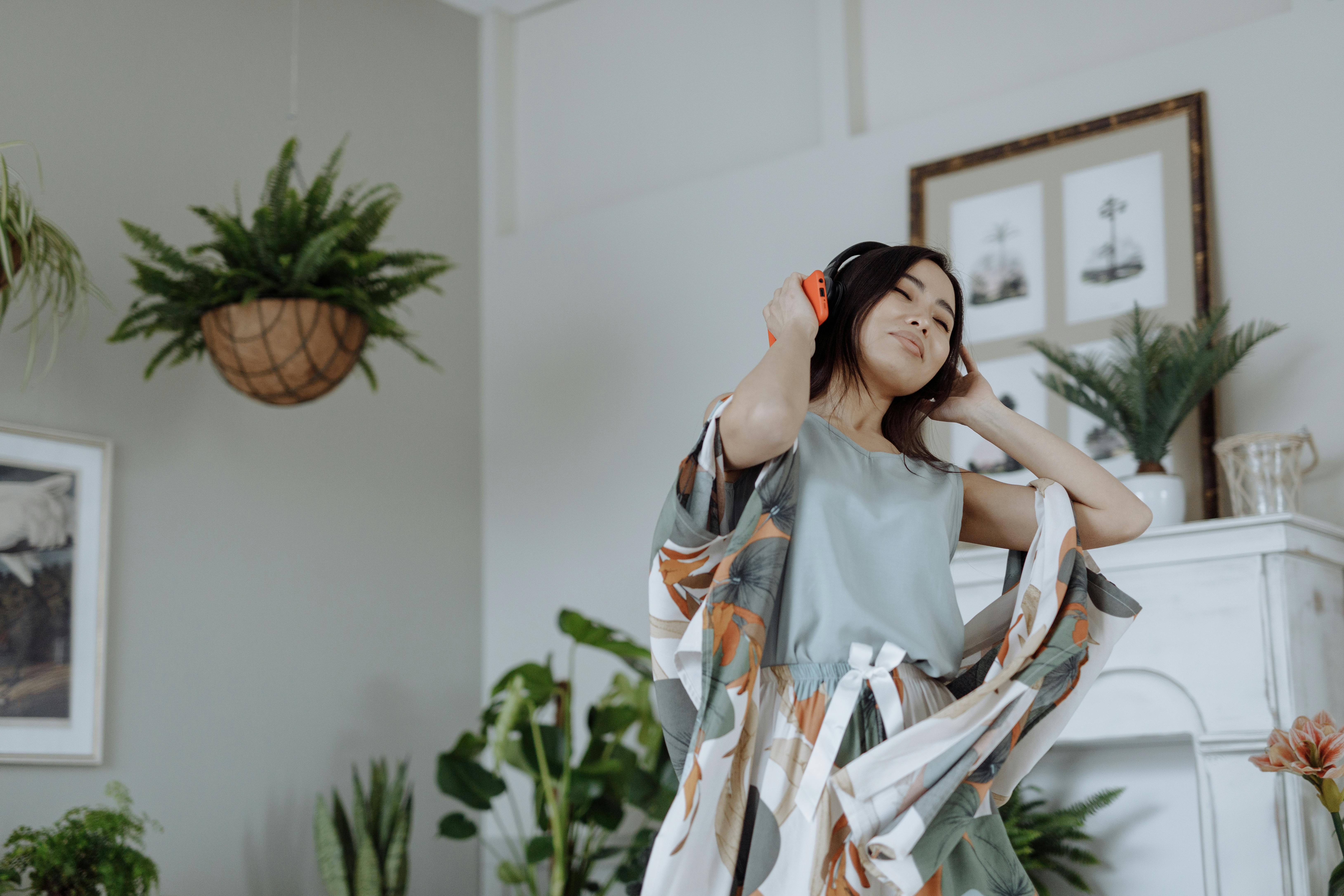 woman in silky pajama wearing headphones and listening to music with eyes closed