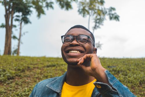 Free Portrait of a young man with eyeglasses smiling outdoors in Abuja. Stock Photo