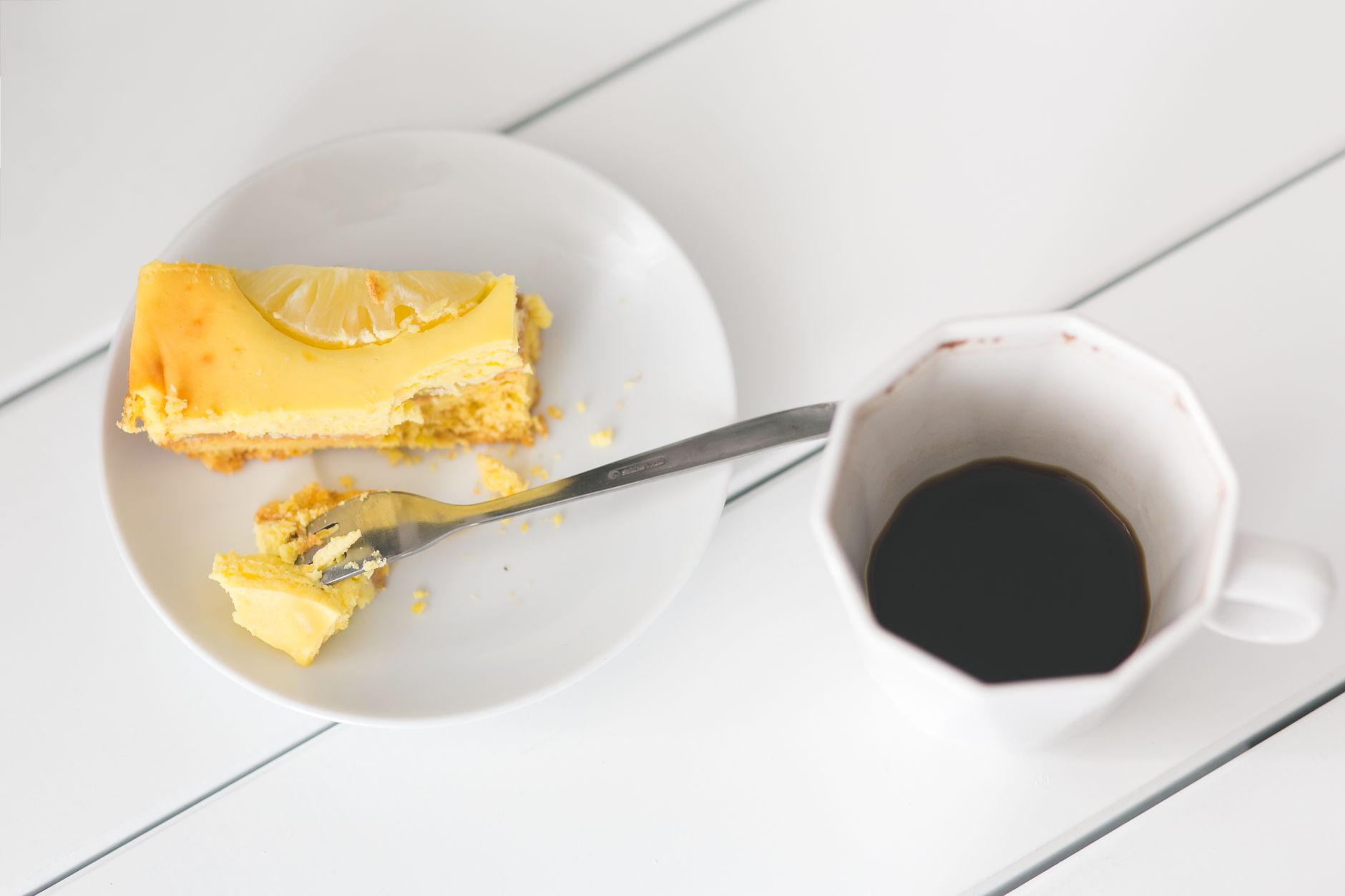 Vegan lemon cheesecake slice on a plate with coffee