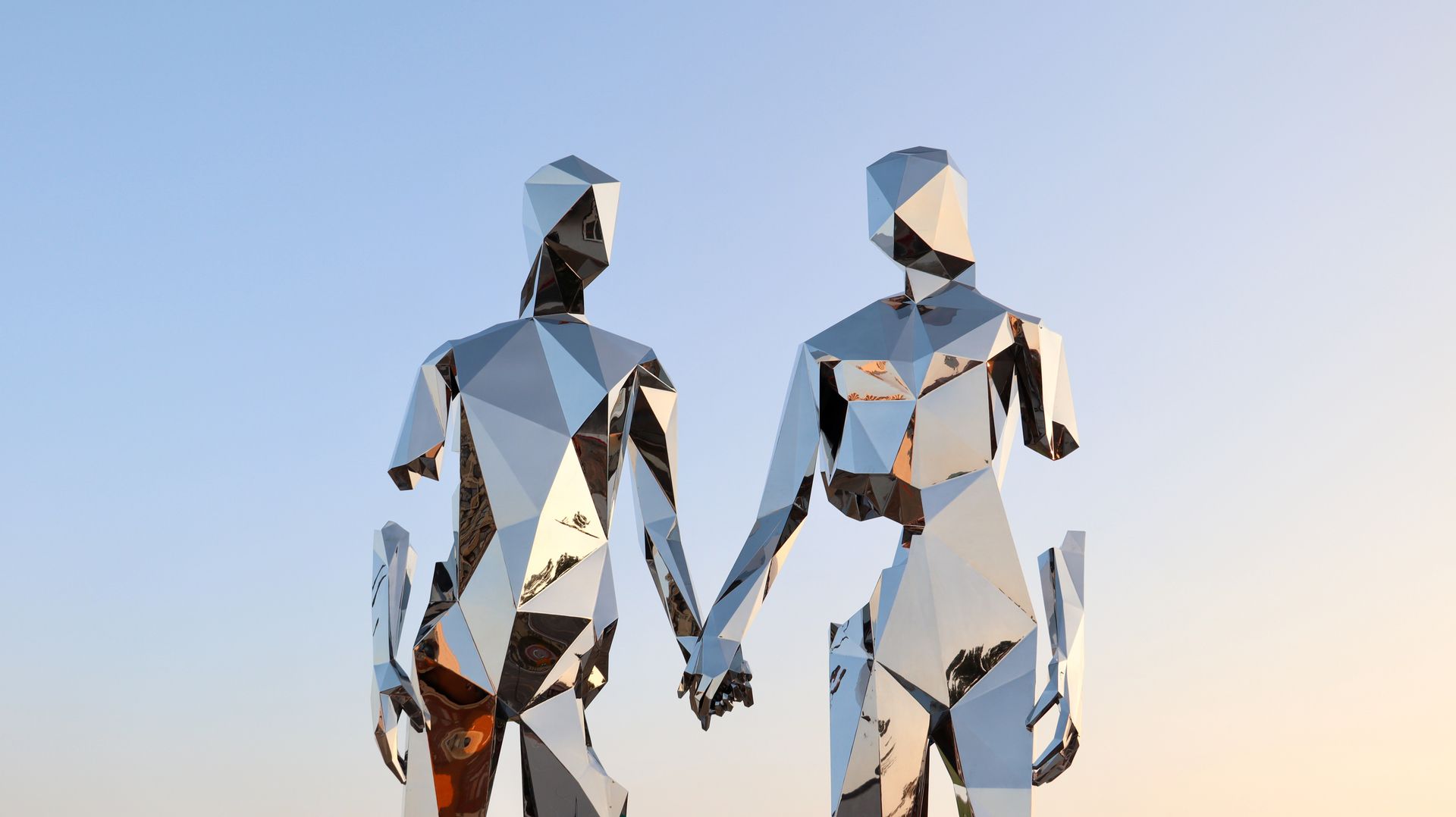 A geometric metal sculpture of a couple holding hands reflecting the sunset sky in Reno, Nevada.