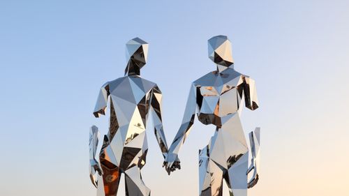 Free A geometric metal sculpture of a couple holding hands reflecting the sunset sky in Reno, Nevada. Stock Photo