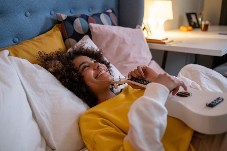 A Woman Lying In Bed With A Ukulele