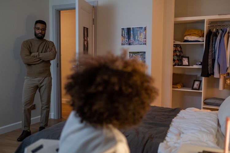 Man Standing On Doorway Talking To HIs Child Inside A Bedroom