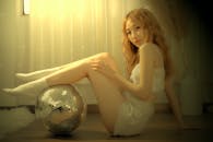 Woman Sitting on the Floor while Her Legs on a Mirror Ball