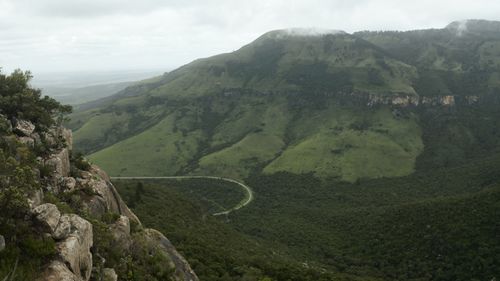 Free Breathtaking aerial view of green mountains and a winding road on a foggy day. Stock Photo