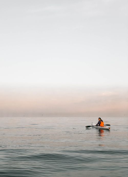 Free A person kayaking alone on a calm ocean during sunrise near Cape Town, South Africa. Stock Photo