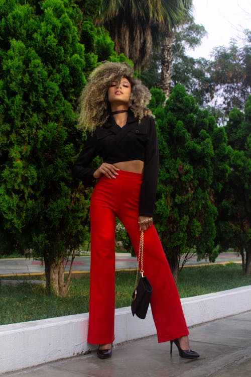 A Woman in a Black Long Sleeves Crop Top and Red Pants Standing Beside a Tree