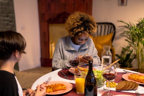 A Woman and a Person Sitting at a Dining Table with Delicious Food and Wine