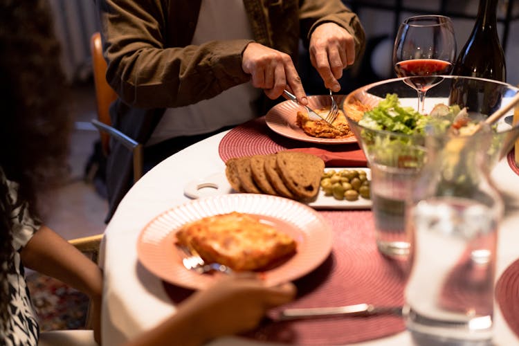 Person Cutting Lasagna With Knife During Dinner At Table 