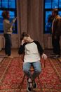 A Boy Sitting on a Chair with Quarreling Parents Behind