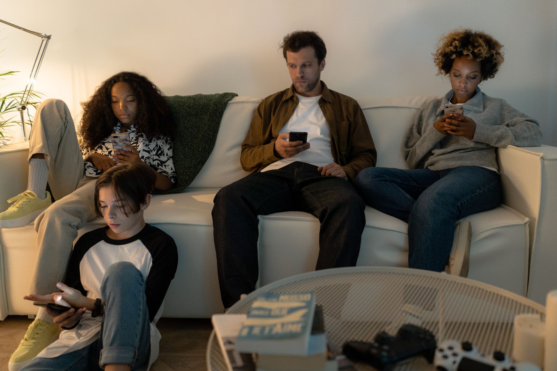 Can Refurbished iPhones Survive Busy Family Life? Real Stories from UK Parents 2 A diverse family sits on a sofa using their smartphones together indoors.