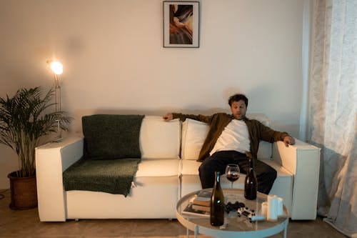 A Man Sitting on a Sofa with a Glass of Wine on the Table