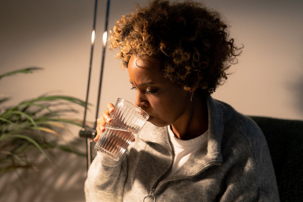 Woman over 40 drinking a glass of water, illustrating cellular hydration and electrolyte balance after 40