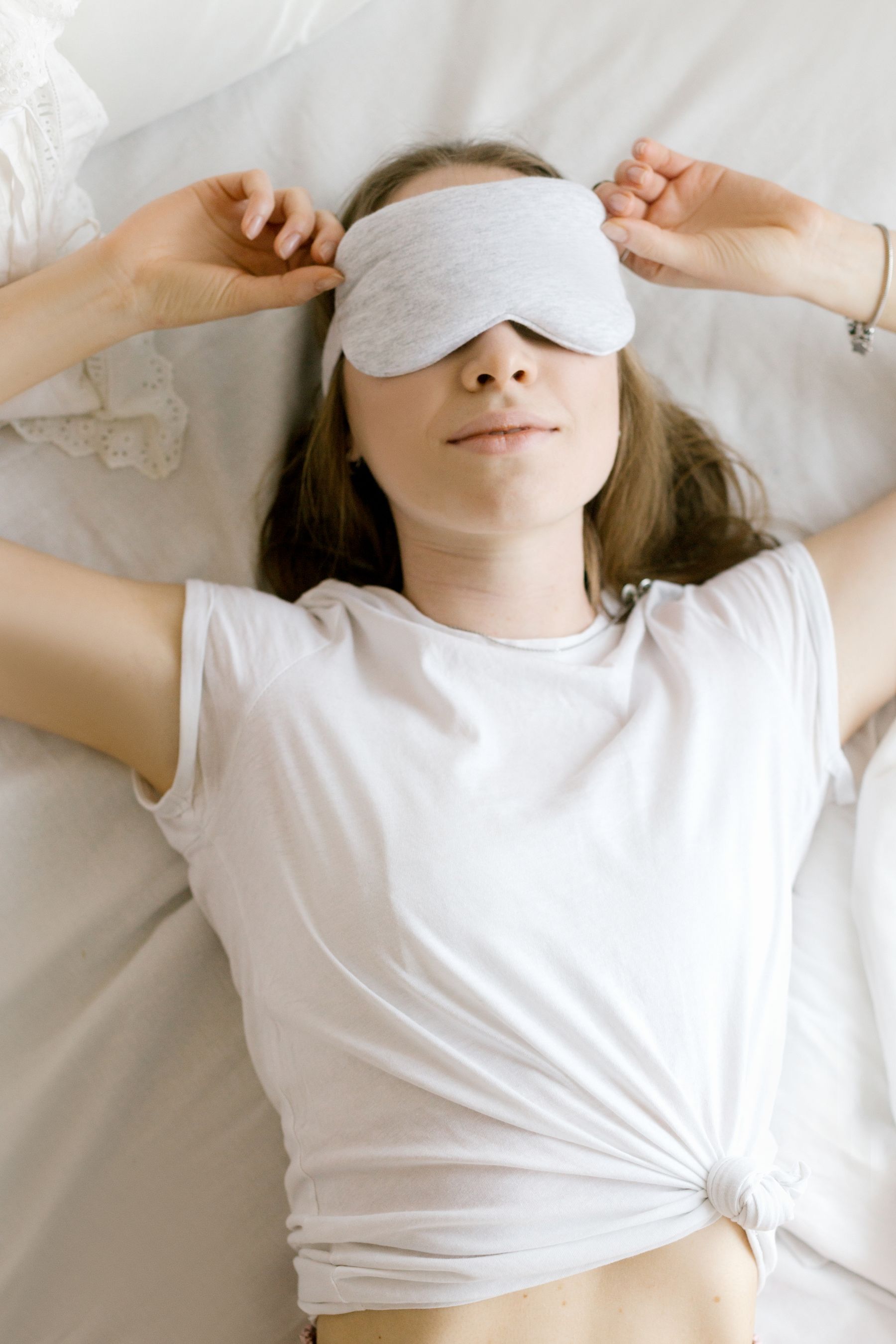 Woman resting in bed while wearing a sleep mask for an everyday comfort routine