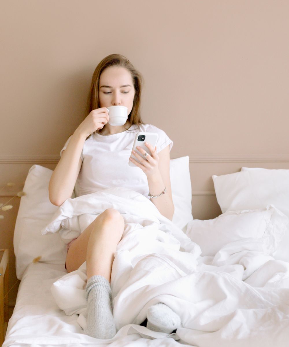 A person holding a phone and coffee, checking in with their partner