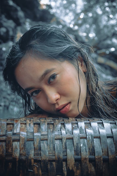 Gentle ethnic female leaning head on wicker jug in nature