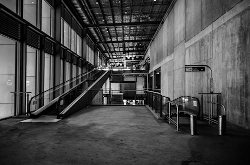 Black and White Photo of a Hall with Escalators