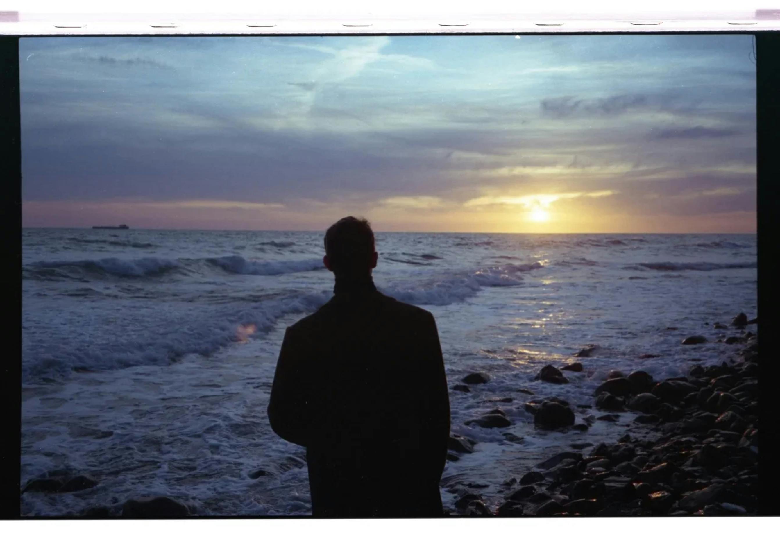 Silhouette of Man Standing on Rocky Shore during Sunset