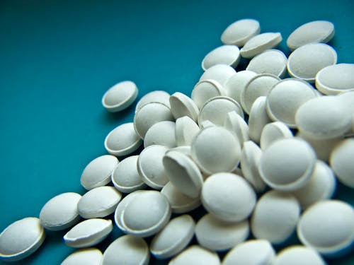 Free High angle of white round tablets for disease treatment scattered on blue background Stock Photo
