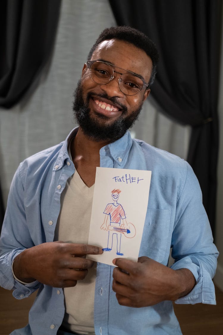 Happy Man Showing A Father Drawing On Paper Sitting In Blue Long Sleeve Shirt