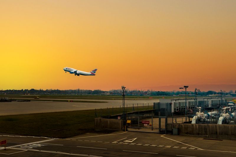 Airplane ascending during sunset at Heathrow Airport, capturing the vibrant sky.
