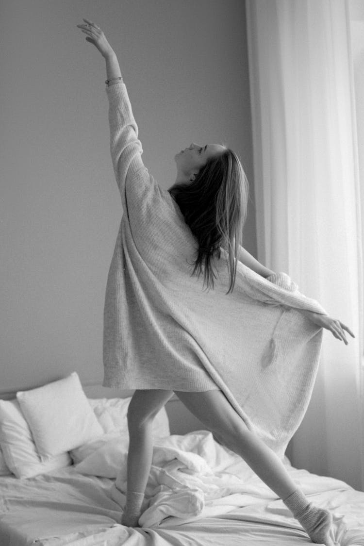 A Woman In Pajama Dancing On Her Bed