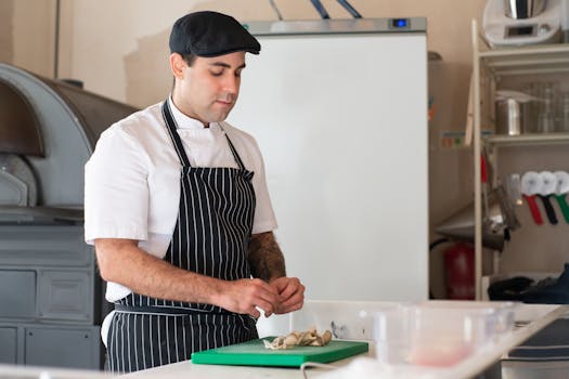 A chef in traditional attire prepares food in a kitchen setting, showcasing culinary skills.