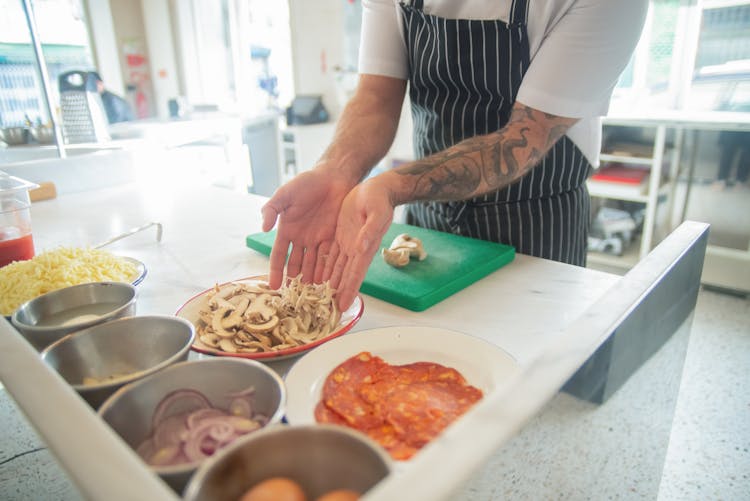 Man In Apron Preparing Ingredients For Cooking Pizza