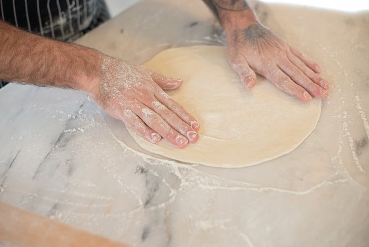 Person Kneading A Dough With Flour On A Table