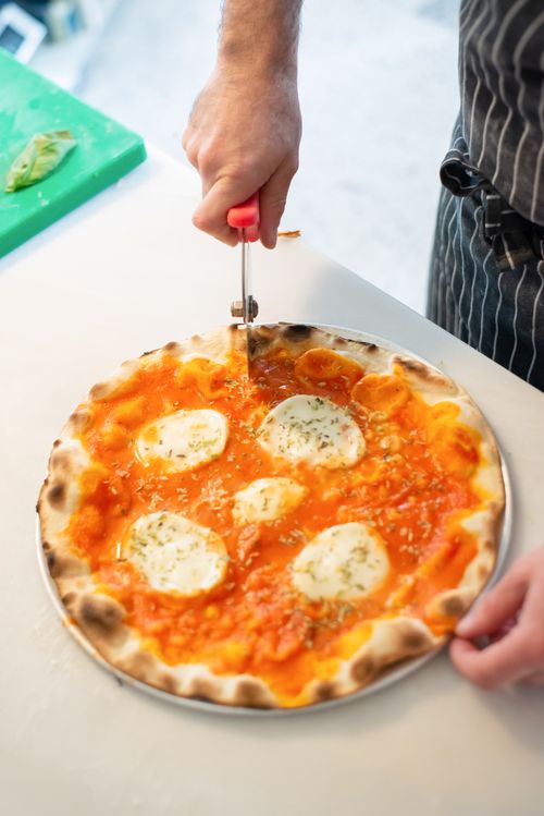 Free Close-up of a chef slicing a delicious Margarita pizza with fresh mozzarella in a kitchen. Stock Photo