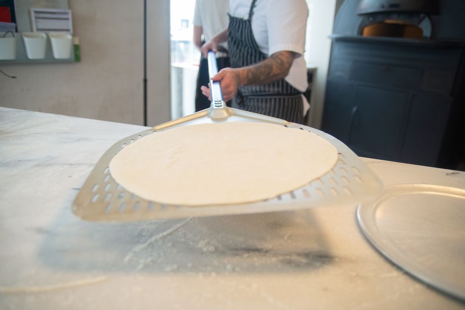 A chef skillfully handling pizza dough in a professional kitchen setting.